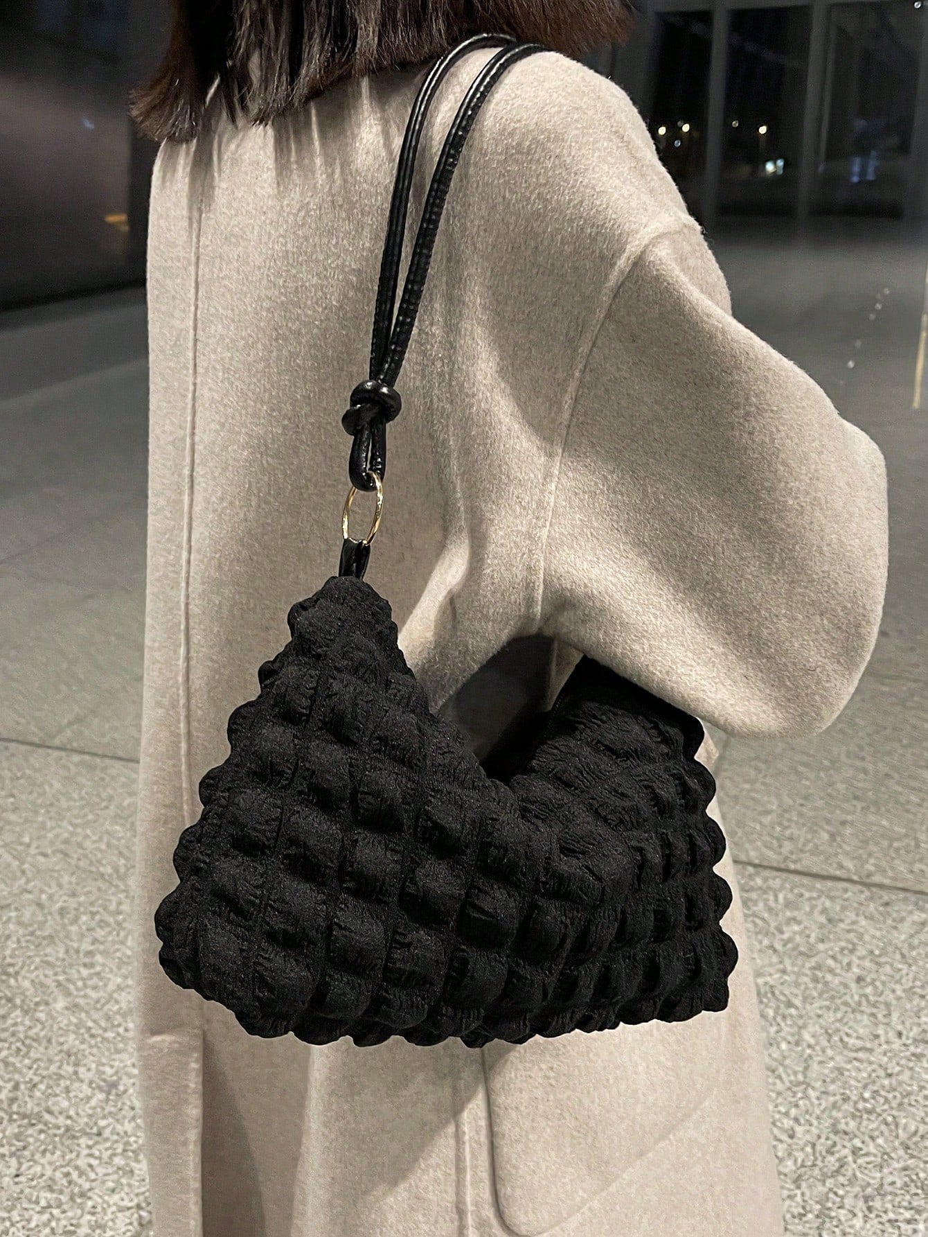 Modern svart damväska med mjukt material och elegant design.